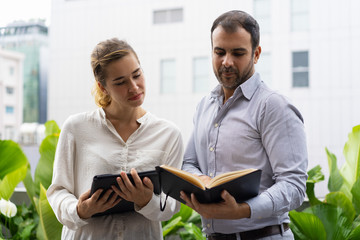 Serious boss and his assistant checking schedule. Two business employees looking at notes during break. Schedule concept