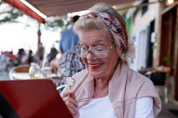 Attractive 78 year old woman during a summer restaurant visit. Authentic, natural, unplugged.
