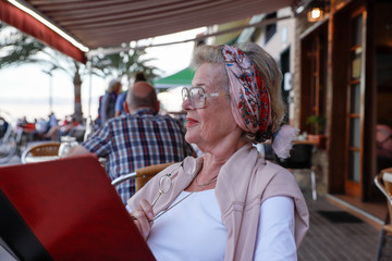 Obraz premium Attractive 78 year old woman during a summer restaurant visit. Authentic, natural, unplugged.
