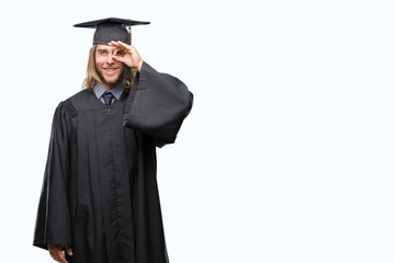 Young handsome graduated man with long hair over isolated background doing ok gesture with hand smiling, eye looking through fingers with happy face.