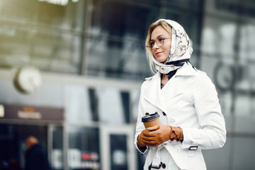 Young stylish pretty woman posing in the city streets and using 