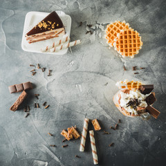 Food frame of chocolate milkshake with dripping sauce, cream, cake and cookie. Flat lay. Top view