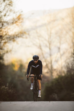 Professional road bicycle racer in action. Men cycling mountain road bike at sunset.