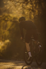Fototapeta na wymiar A side shot of a professional slim cyclist riding up a mountain