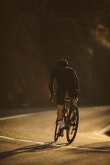 A side shot of a professional slim cyclist riding up a mountain