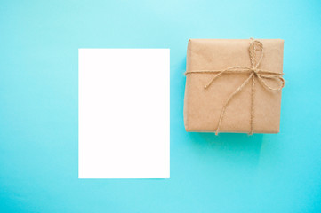 Gift box wrapped in brown colored craft paper and tied with cord on blue background with copyspace.