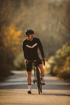 Professional road bicycle racer posing. Men cycling mountain road bike at sunset.