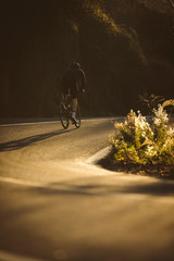 A side shot of a professional slim cyclist riding up a mountain