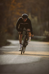 Professional road bicycle racer in action. Men cycling mountain road bike at sunset.