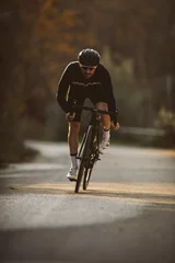 Foto op Plexiglas Professional road bicycle racer in action. Men cycling mountain road bike at sunset. © juananbarros
