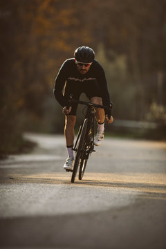 Professional road bicycle racer in action. Men cycling mountain road bike at sunset.