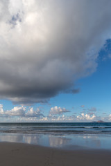 Naklejka na ściany i meble Clouds hovering over the beach