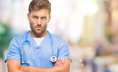 Young handsome doctor nurse man over isolated background skeptic and nervous, disapproving...