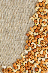 Mix of nuts lying on a background of brown cloth burlap.