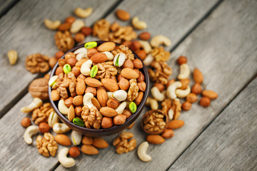 Wooden bowl with nuts on a wooden background, near a bag from burlap.