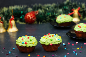 Homemade cupcakes covered with cream and pastry decorations are located on a dark background