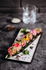 Various kinds of tasty sushi served on black stone