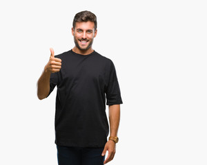 Young handsome man over isolated background doing happy thumbs up gesture with hand. Approving expression looking at the camera with showing success.