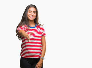 Young beautiful arab woman over isolated background smiling friendly offering handshake as greeting and welcoming. Successful business.