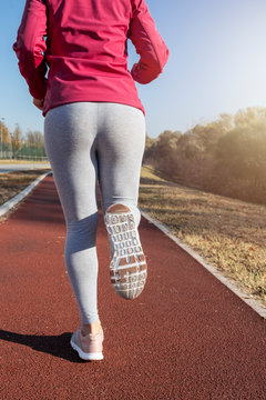 Picture of young attractive fitness girl jogging during sunrise. Pretty female jogger running outdoors.