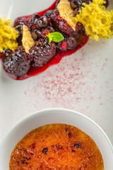 creme brulee with hot forest fruit served on white plate in modern restaurant, product photography for gastronomy