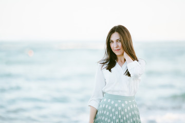Marine female portrait. Attractive woman in green skirt walks along the shore before the sea