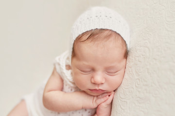Fototapeta na wymiar Cute newborn little girl sleeping on light background. Baby goods packaging template. Closeup portrait of newborn baby with smile on face. Healthy and medical concept. Eco conception. Nursery.
