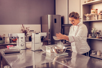 Obraz premium Positive skilled woman holding a flour sifter