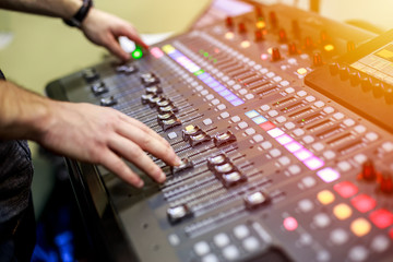Person adjusting audio mixing console on music studio