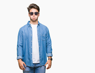 Fototapeta premium Young handsome man wearing sunglasses over isolated background puffing cheeks with funny face. Mouth inflated with air, crazy expression.