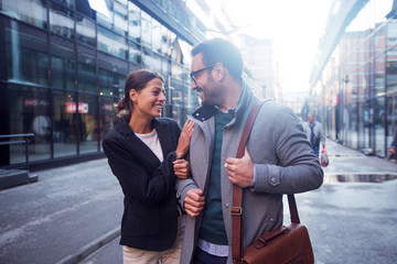 Image of successful businesswoman and businessman standing near office building