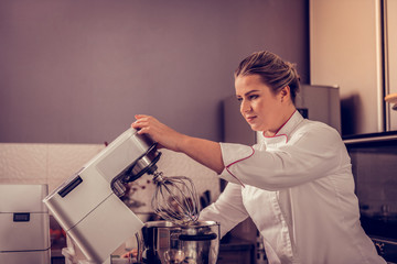 Professional female pastry chef using kitchen machine