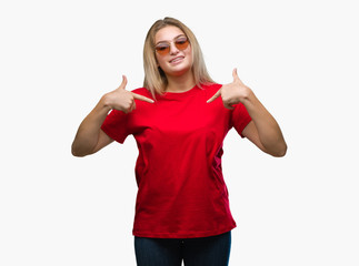 Obraz na płótnie Canvas Young caucasian woman wearing sunglasses over isolated background looking confident with smile on face, pointing oneself with fingers proud and happy.