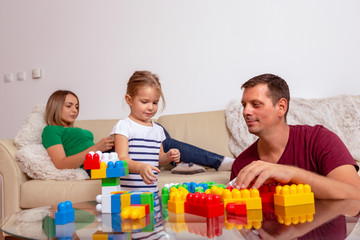 Smiling man and little girl playing with cubes together at home.