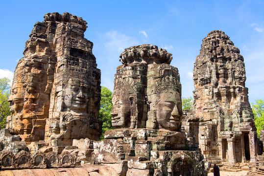 Stone Faces of Bayon Temple in Angkor Thom, Siem Reap, Cambodia. Ancient Khmer architecture travel shot of historic Prasat Bayon towers with a clear blue sky background and copy space for text.