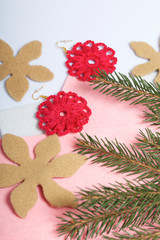 Knitted earrings on the background of felt fabric. Near spruce branch.