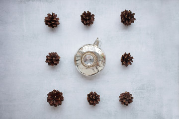 Obraz na płótnie Canvas holidays, winter and celebration concept - Christmas composition. pine cones, glass toy on cement background. Flat lay, top view