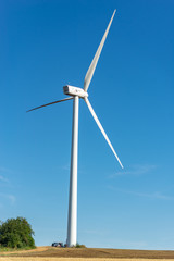 Grande &eacute;olienne avec des techniciens &agrave; son pied sur fond de ciel bleu