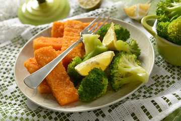 fish sticks with broccoli and lemon garnish