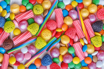 mixed multicolored candies on white wooden background.