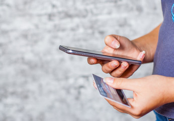 Close-up woman's hands holding a credit card and using smartphone for online shopping