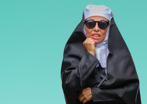 Middle age senior catholic nun woman wearing sunglasses over isolated background looking stressed and nervous with hands on mouth biting nails. Anxiety problem.