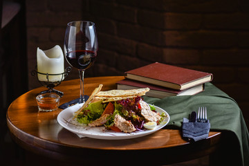 Serving at the restaurant a salad of fresh vegetables with meat and croutons. Dish with ingredients of meat and vegetables on the plate on a black wooden background, top view. Black background for