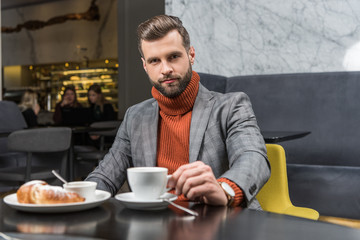 handsome man in formal wear looking at camera during lunch in restaurant