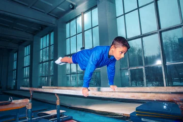 Gardinen The little boy is engaged in sports gymnastics on a parallel bars at gym. The performance, sport, acrobat, acrobatic, exercise, training concept © master1305