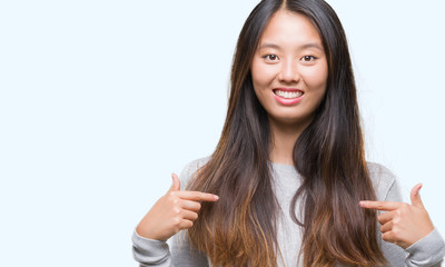 Young asian woman over isolated background looking confident with smile on face, pointing oneself with fingers proud and happy.