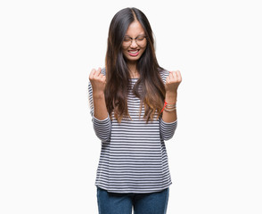 Young asian woman wearing glasses over isolated background very happy and excited doing winner gesture with arms raised, smiling and screaming for success. Celebration concept.