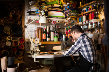 Fototapeta na wymiar Attractive man worker working on stitches for belt