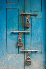 Old blue wooden door with three padlocks. bolts on the door.