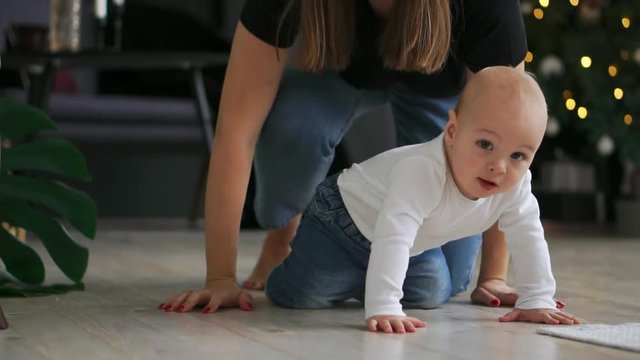 Little kid with toy in mouth crawling on sofa. Close up of naked baby in diapers walking on bed with toy. Funny child learning walk. Cute baby crawl at home. Sweet child play